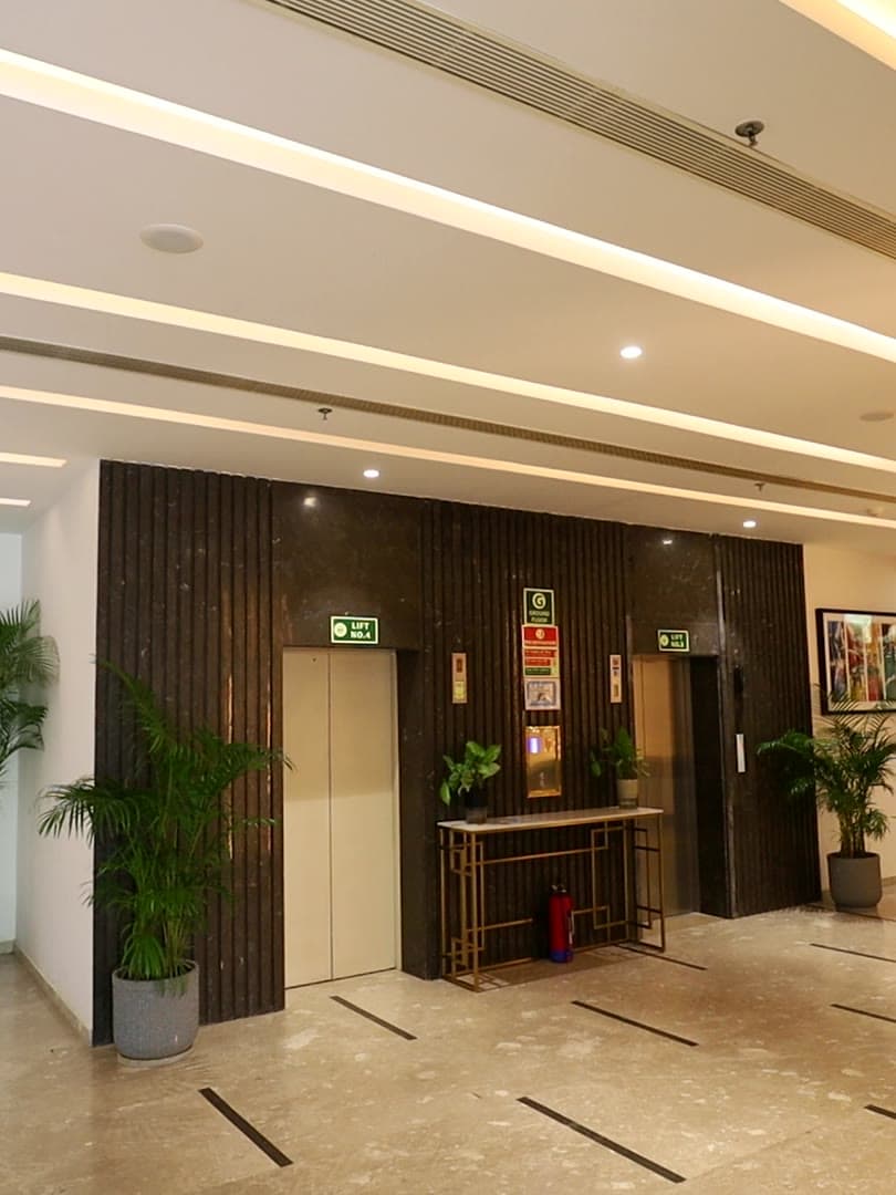 The ground-floor lift lobby at a JDKD building, with fluted stone cladding, planters and a marble reception counter.