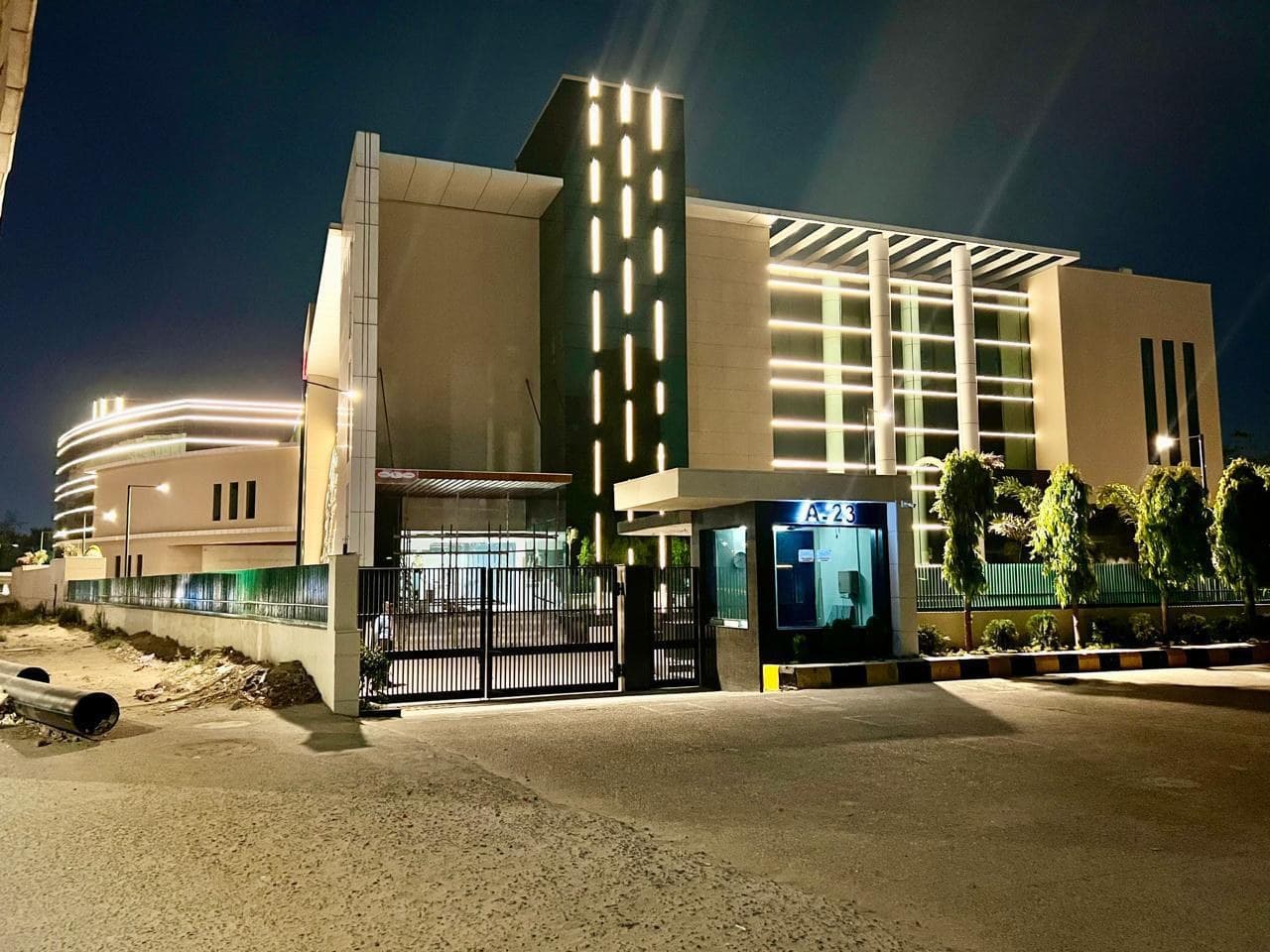 JDKD Corporate Park at A-23, Mohan Co-operative Industrial Estate, lit up at night behind its gatehouse.