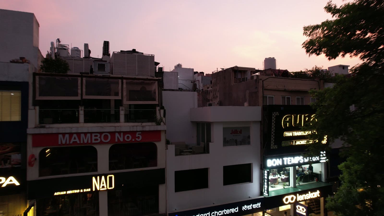 The full M-39 frontage at dusk, the JDKD mark on its facade and Standard Chartered at street level.
