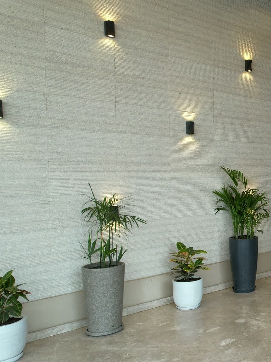 Architectural fluted stone wall with geometric sconce lighting and planters